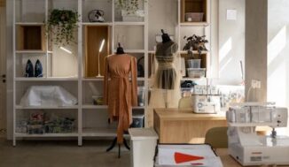 A fashion studio with mannequins, sewing machines, and organized shelves, bathed in natural sunlight.